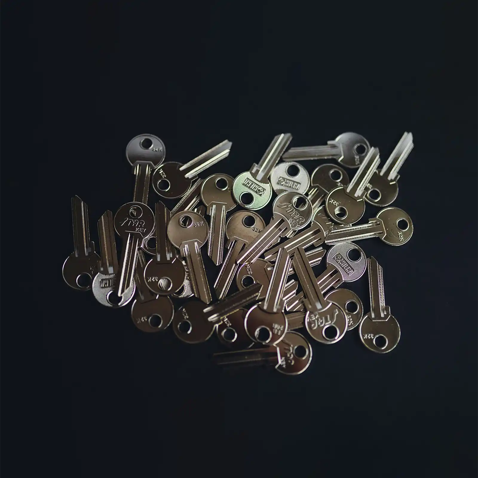 A pile of keys on a dark background.