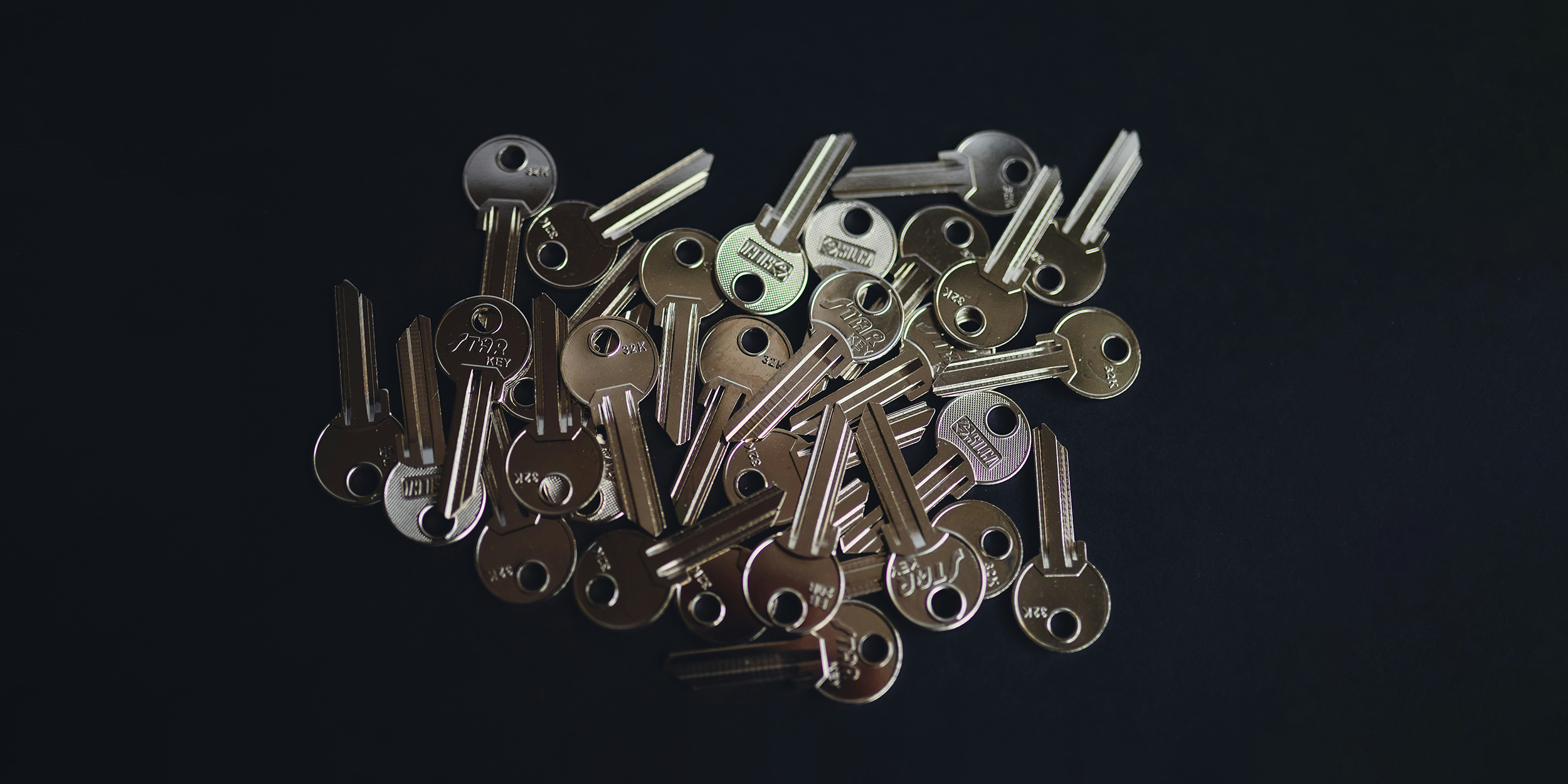 A pile of keys on a dark background.